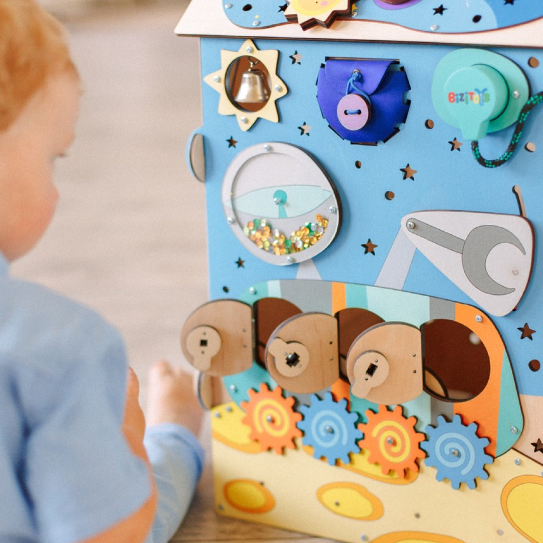 toddler turning gears on activity board